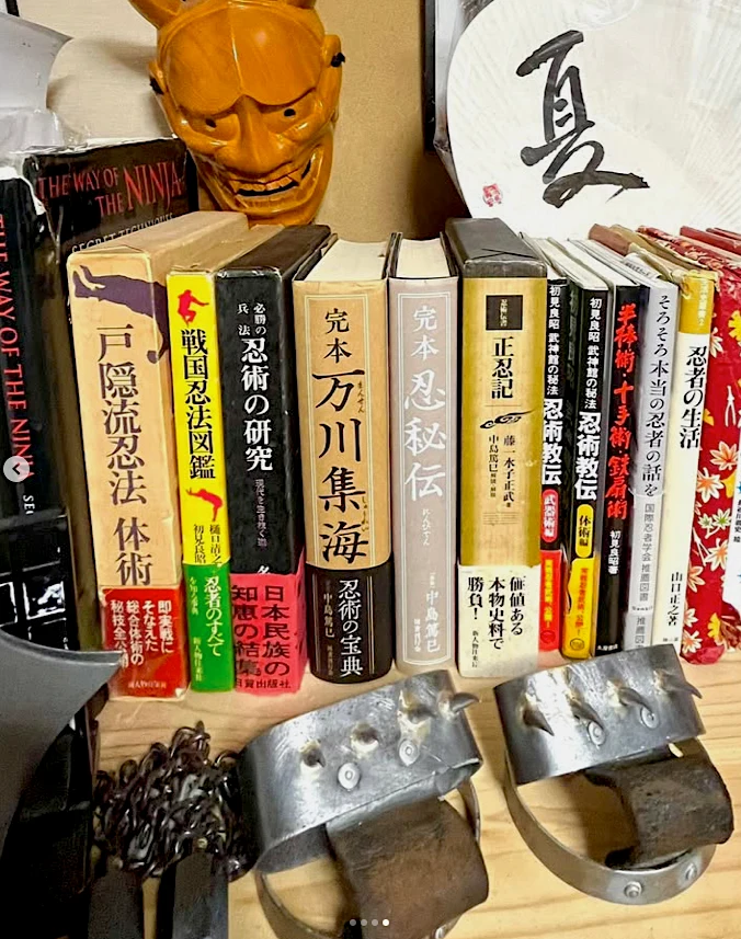 ジェローム・パイエットの所蔵する忍術・忍法の書籍と、手前に置かれた一対の手鉤。