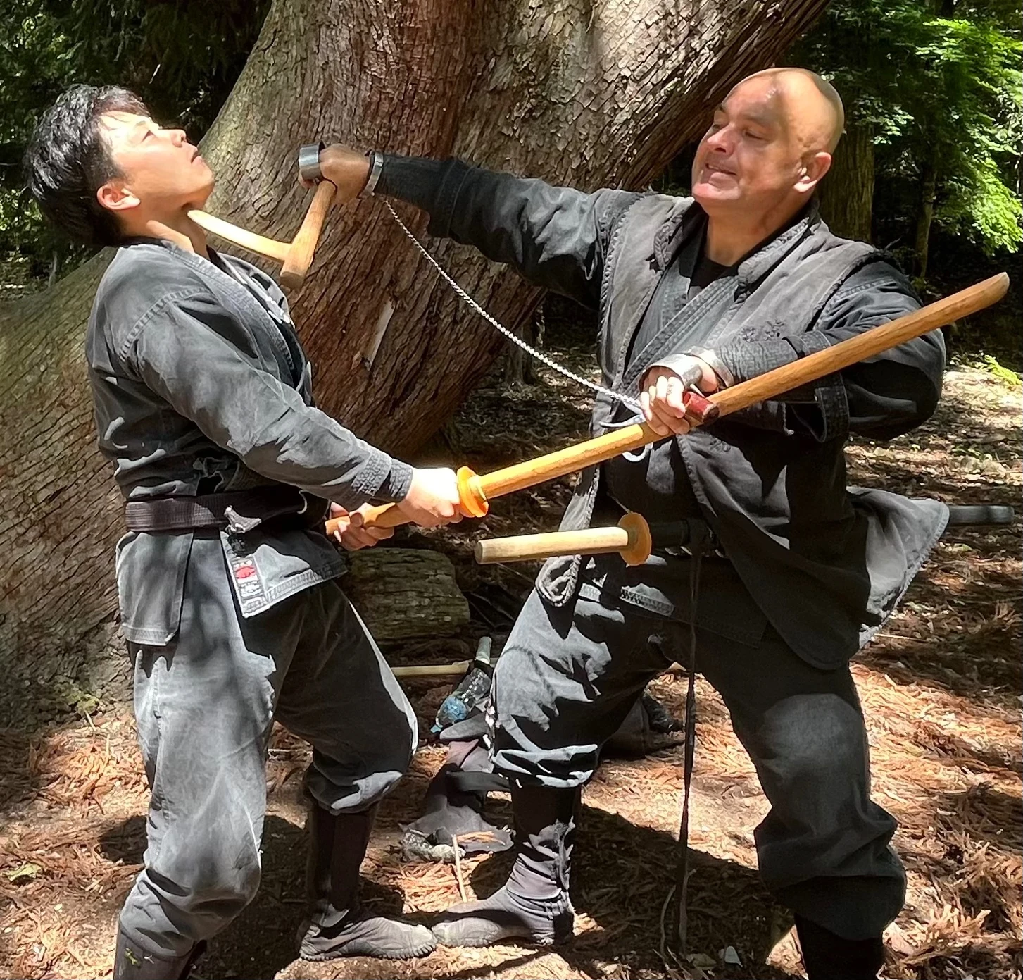 一人が後方へ傾き、もう一人が道具を装着した手を首元へ伸ばしている。